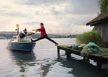 Mitarbeiter balanciert zwischen Steg und Fischerboot Thumbnail